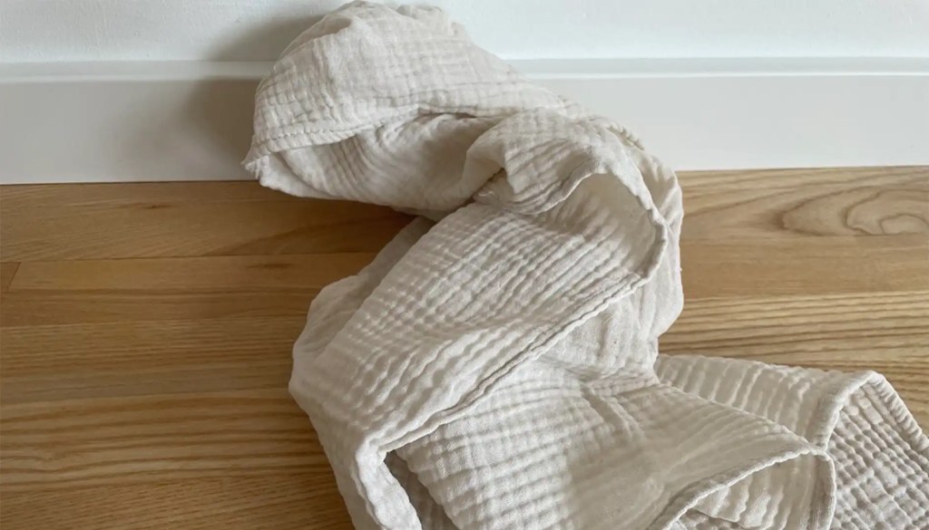 Spucktuch leigt bei weißer Fußleiste und Holzfußboden