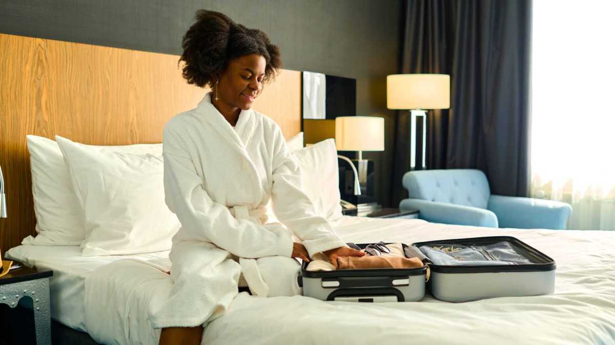 Junge Frau sitzt auf dem Hotelbett.