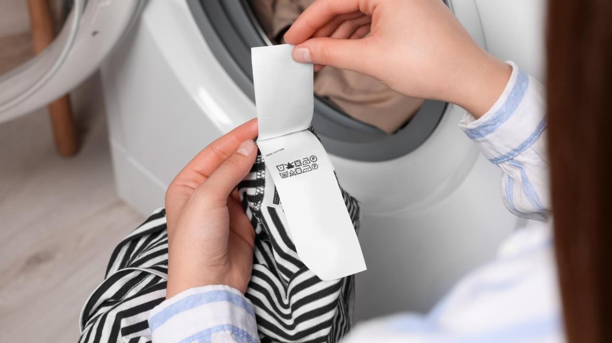 Frau guckt auf die Waschanleitung einer zweifarbigen Bluse.