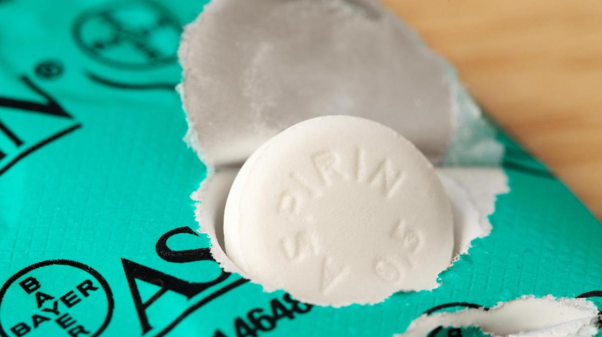 Aspirin-Tabletten werden aus einer grünen Packung gedrückt.