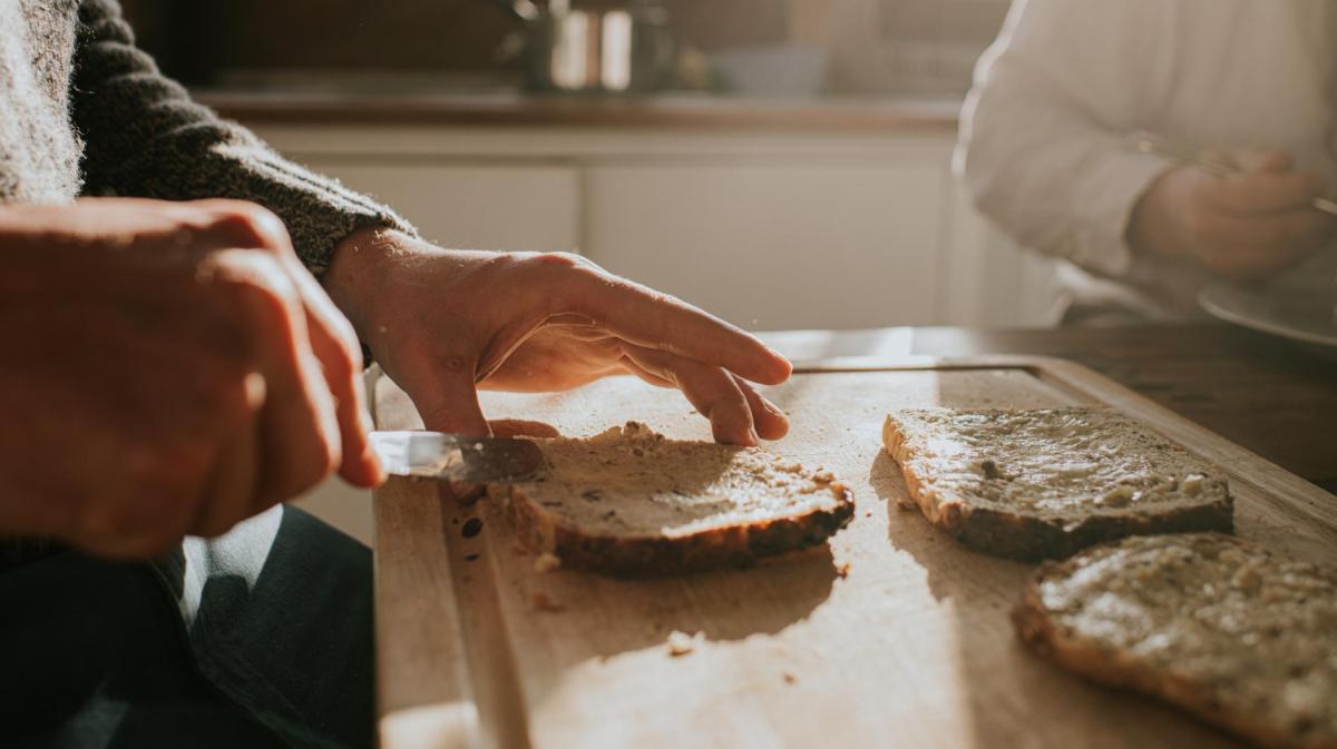 Frau schmiert sich ein Brot.