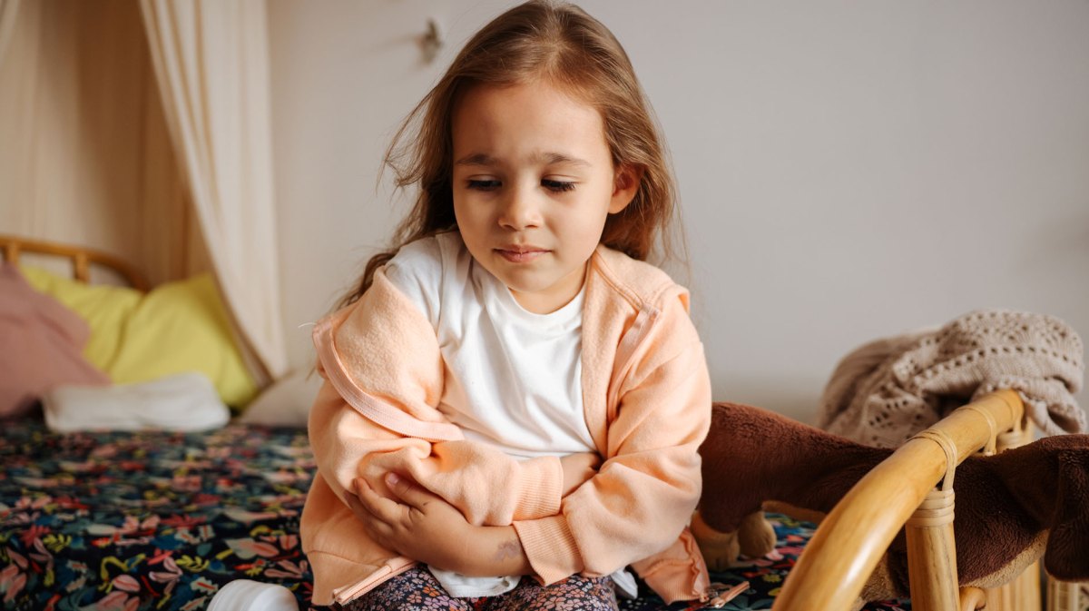 Mädchen, ca. 6 Jahre alt, hält sich den Bauch.