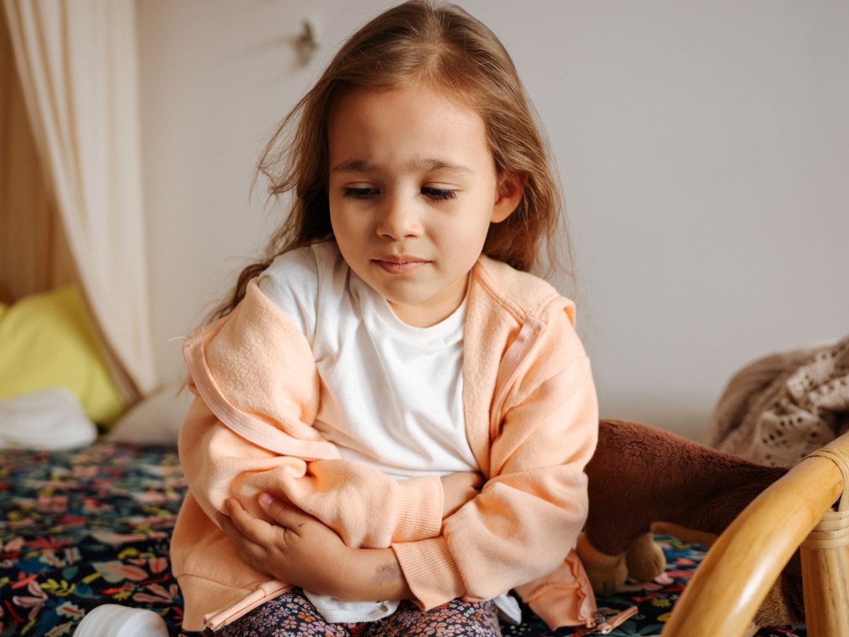 Mädchen, ca. 6 Jahre alt, hält sich den Bauch.