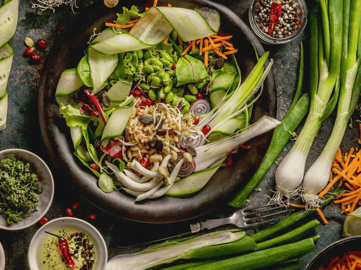 verschiedene Salate und Zutaten auf einem dunklen Tisch