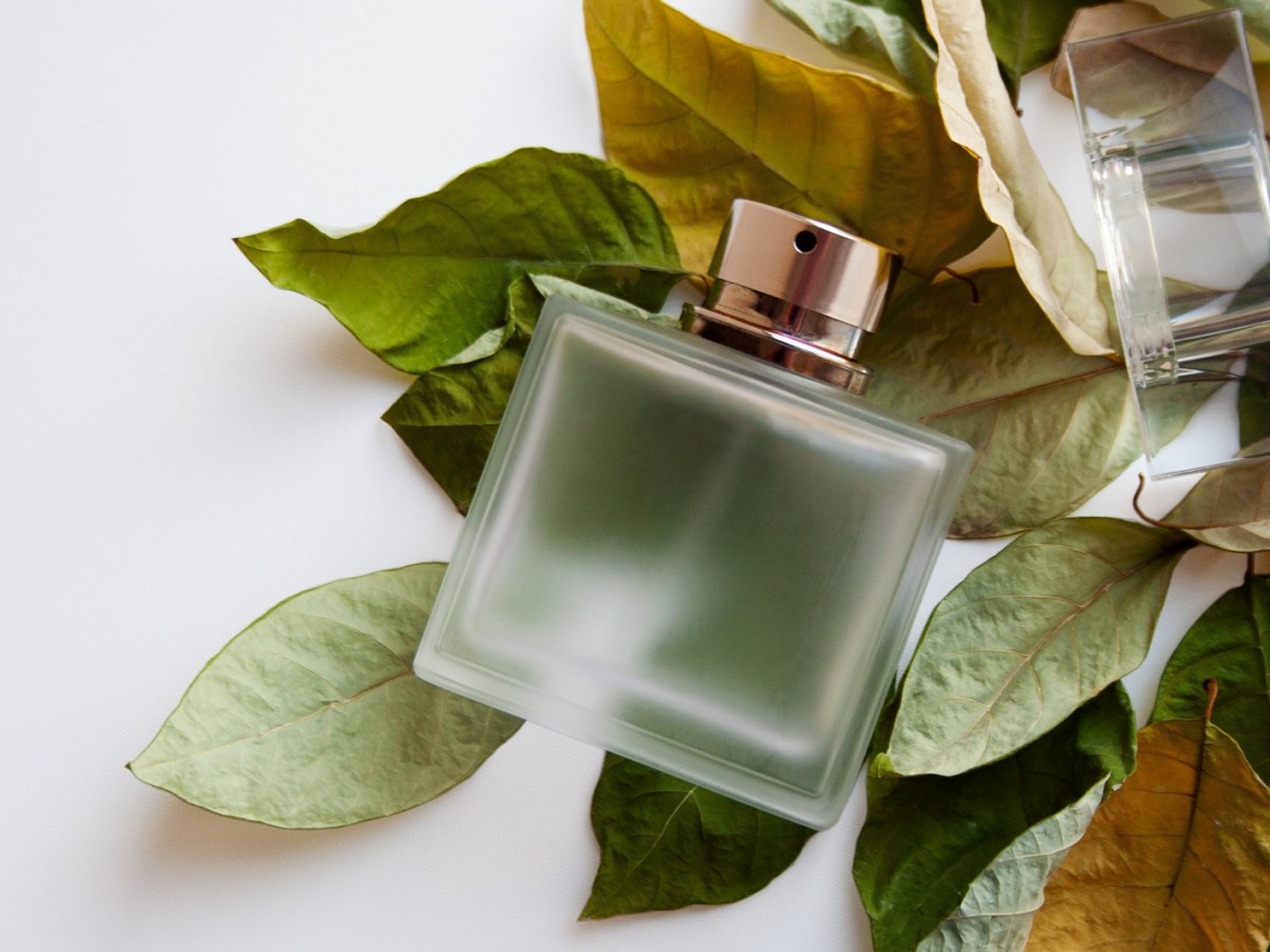 Parfum-Flakon, der auf getrockneten Herbst-Bl&auml;ttern liegt.