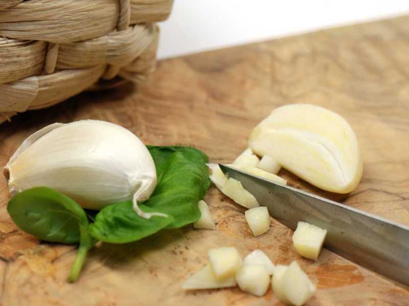 Knoblauch wird auf einem Schneidebrett geschnitten