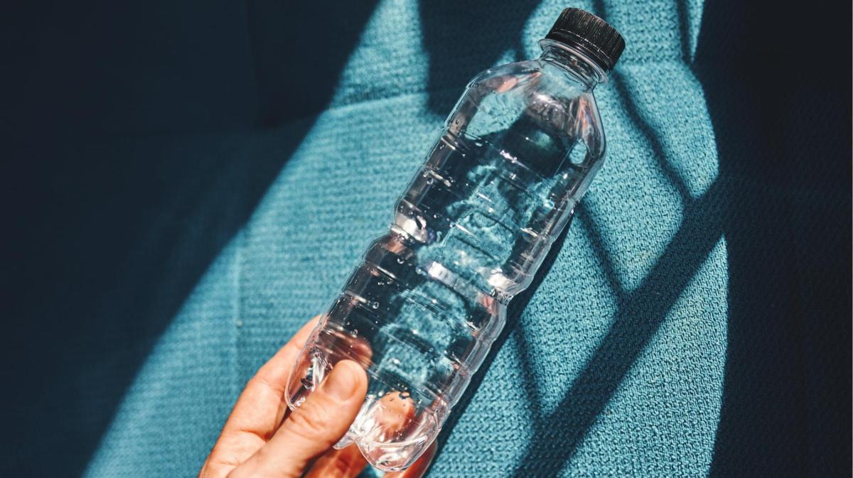 Person hält eine Flasche Wasser in der Hand.