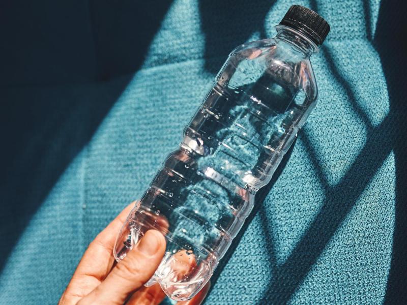 Person hält eine Flasche Wasser in der Hand.