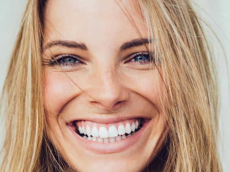 Junge blonde Frau mit blauen Augen strahlt in die Kamera.