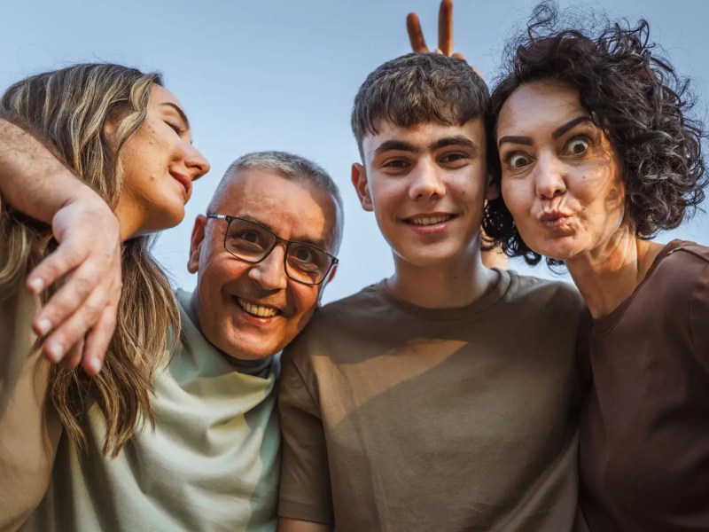 Vierköpfige Familie mit Kindern im Teenageralter macht ein lustiges Foto.