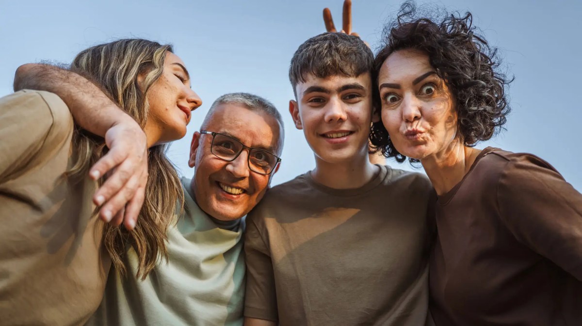 Vierköpfige Familie mit Kindern im Teenageralter macht ein lustiges Foto.
