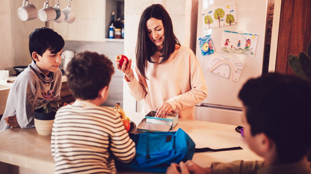 Mutter packt die Brotdosen der Kinder am Abend, die Kids und der Vater gucken zu.
