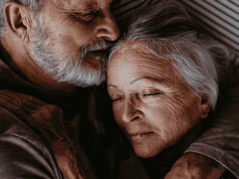 Älteres Paar liegt im Bett und kuschelt.