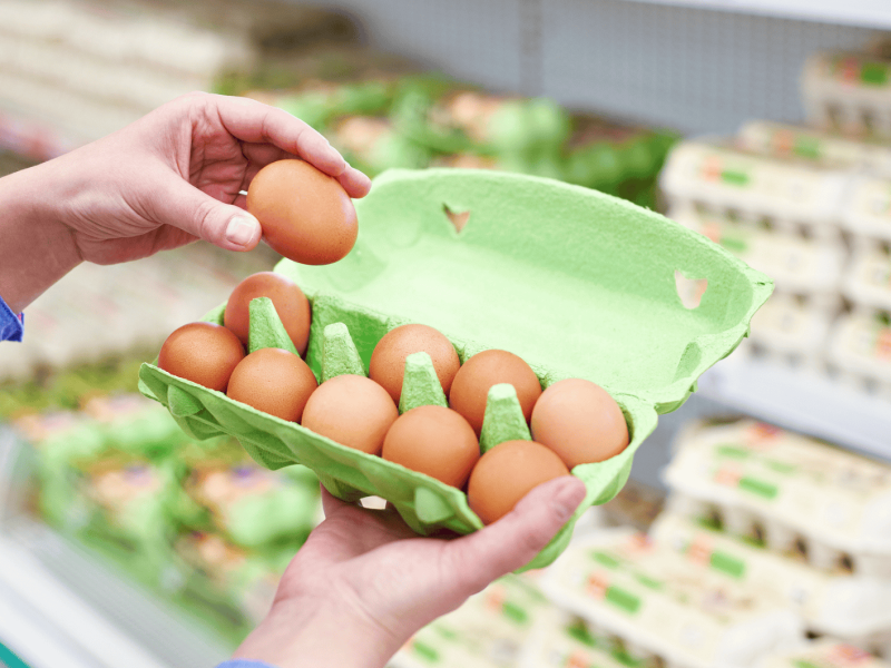 Person öffnet Eierkarton im Supermarkt.