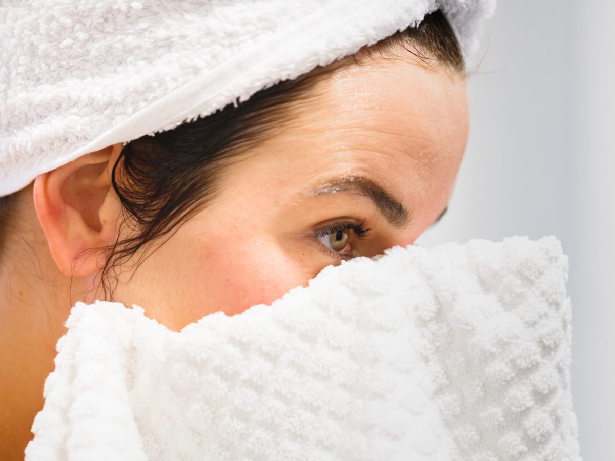 Frau trocknet sich Gesicht mit Handtuch ab