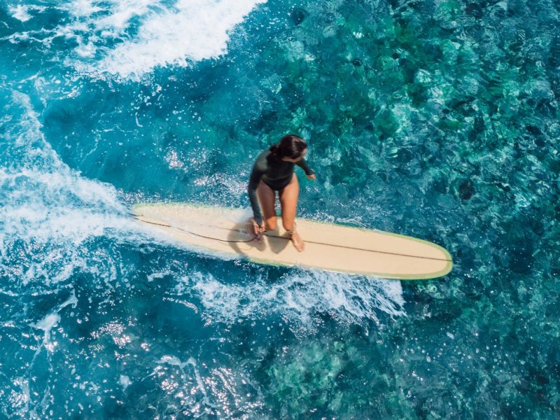 Surferin in kristallblauem Wasser