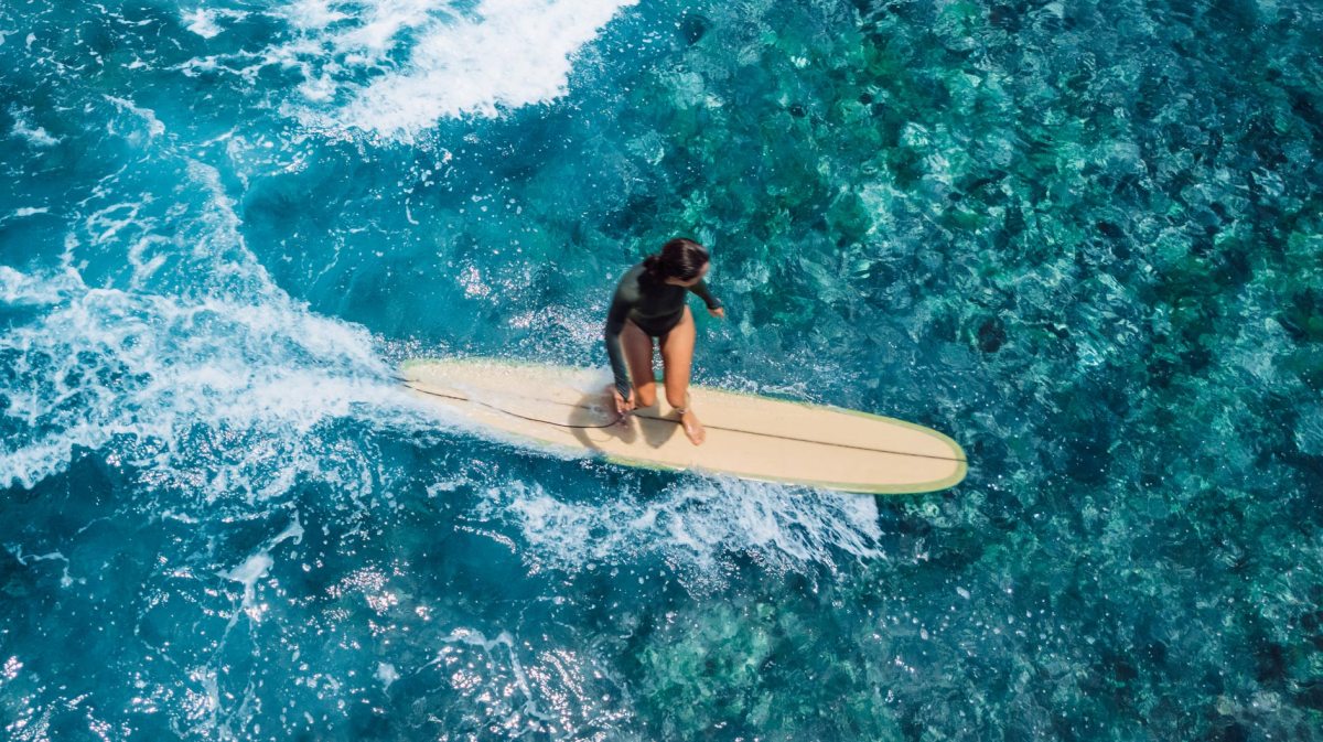 Surferin in kristallblauem Wasser