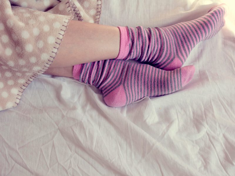 Junge Frau schläft mit rosa gestreiften Socken