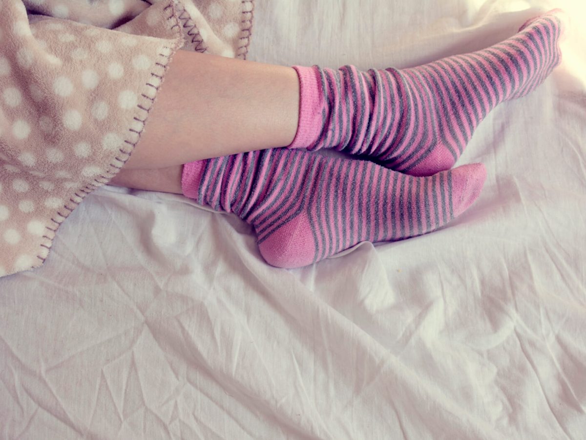 Junge Frau schläft mit rosa gestreiften Socken