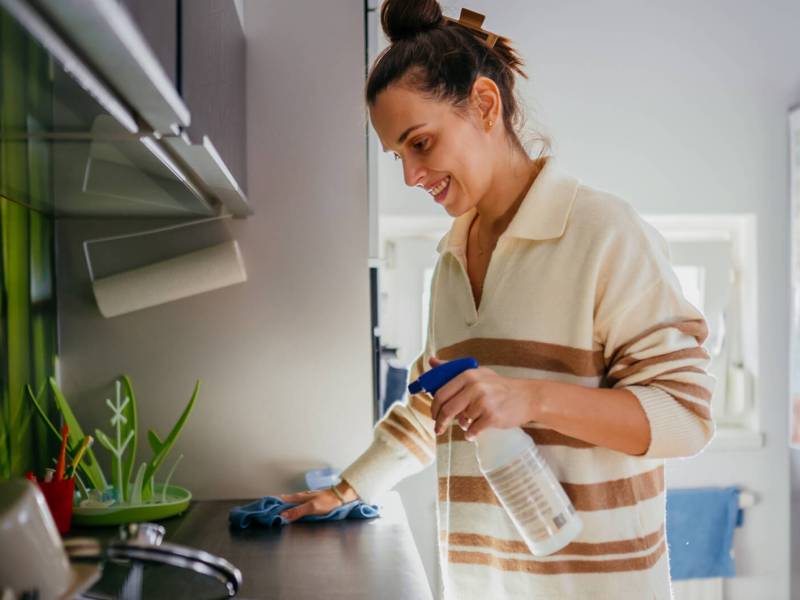 Junge Frau putzt Küchenfläche
