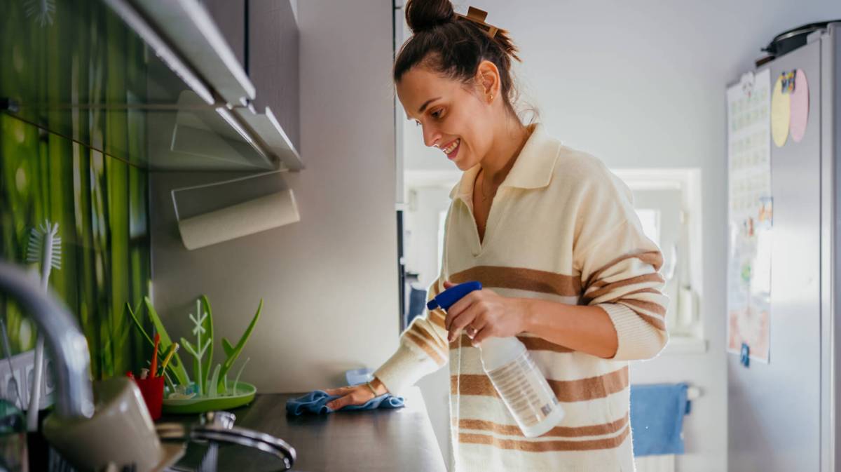 Junge Frau putzt Küchenfläche