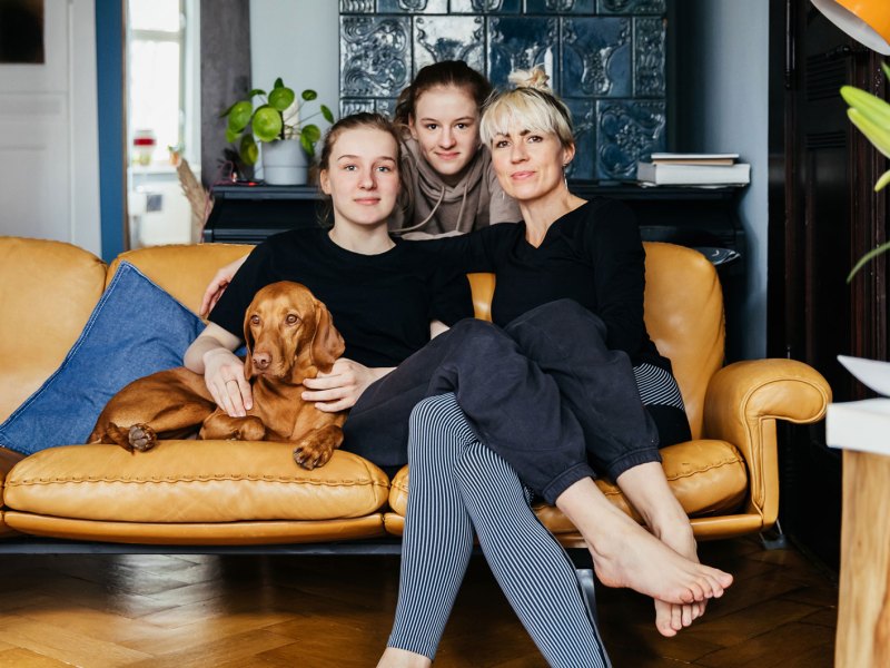 Mutter mit zwei Teenager T&ouml;chtern auf Sofa mit Hund