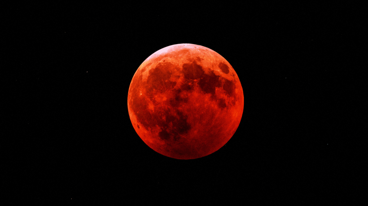 Roter Vollmond in dunklem Nachthimmel.