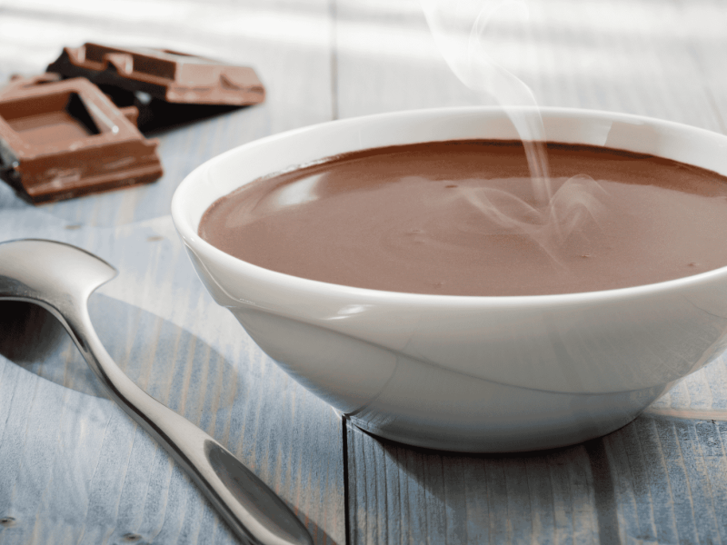 Eine weiße Schüssel mit dampfender Schokoladensuppe.