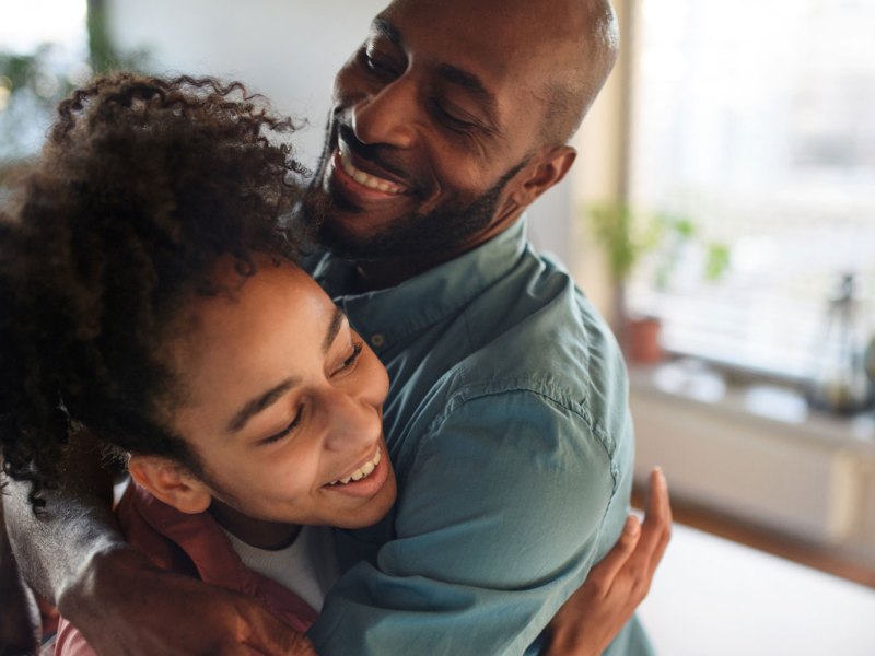 Tochter und Vater umarmen sich, beide lachen.