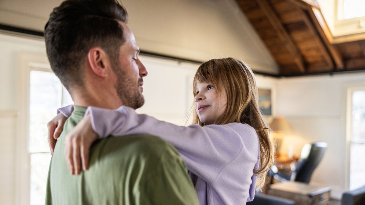 Vater hält seine Tochter auf dem Arm und beide schauen sich liebevoll in die Augen.