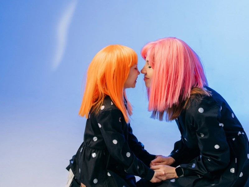 Mutter und Kind mit Per&uuml;cken halten die Nasen aneinander