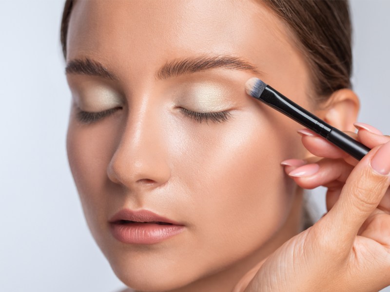 Frau, die gerade geschminkt wird und ein Augen-Make-up erh&auml;lt.