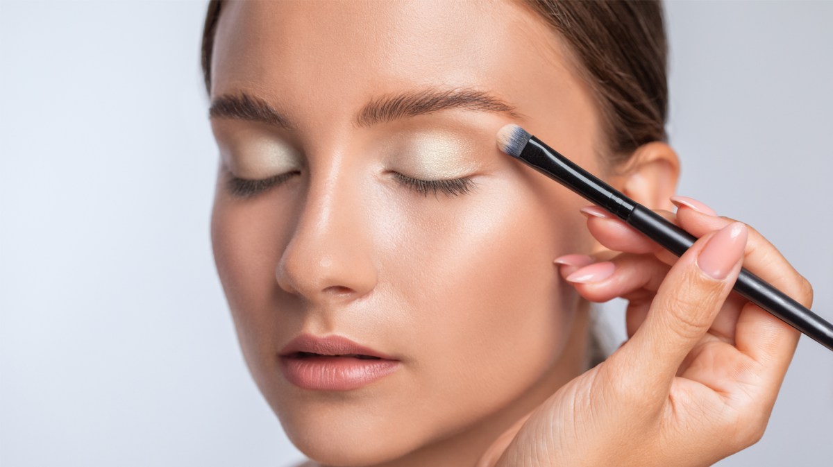 Frau, die gerade geschminkt wird und ein Augen-Make-up erhält.