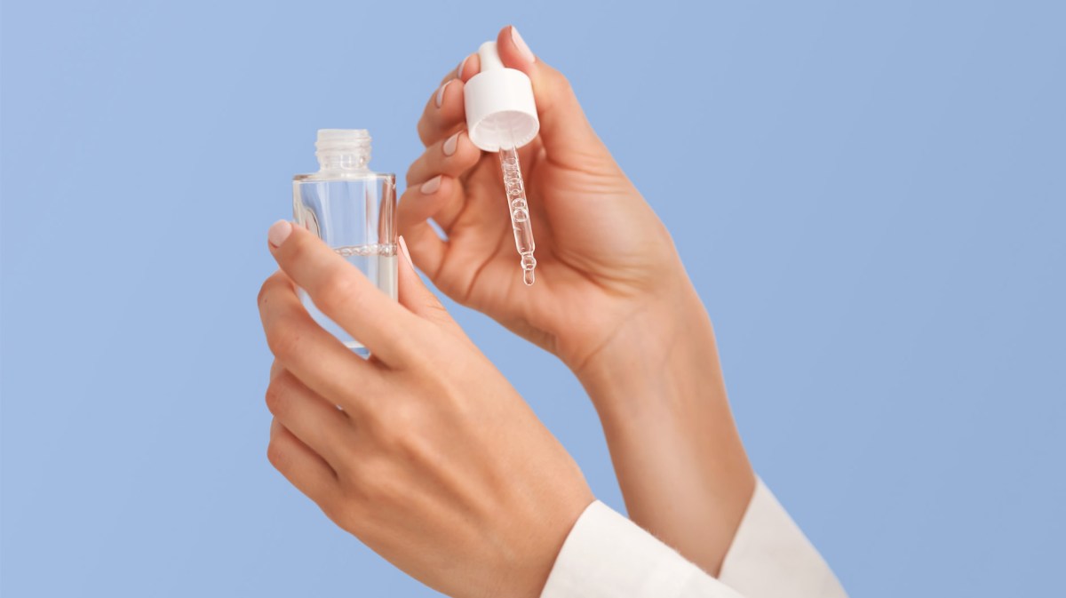 Zwei Hände mit einem Serum aus dem ein Tropfen auf die Hände fällt.