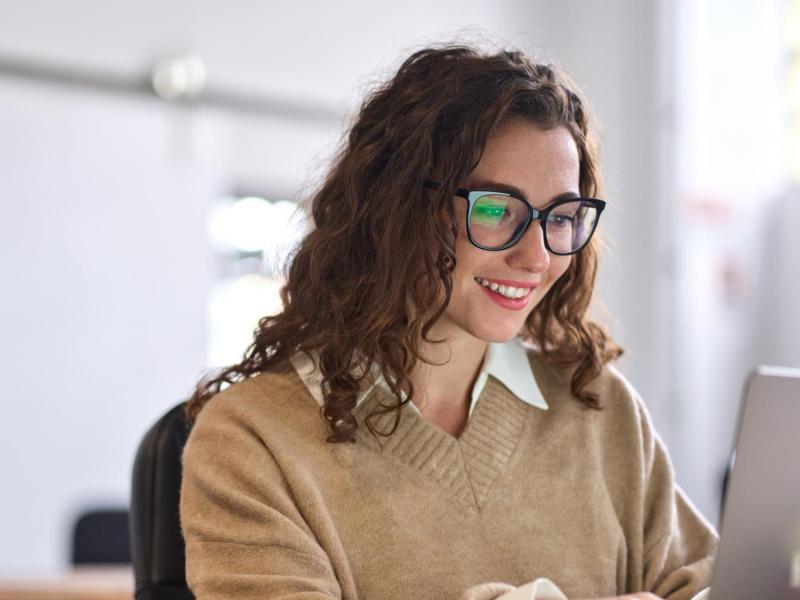 Junge Frau mit dunklen Locken und Brille.