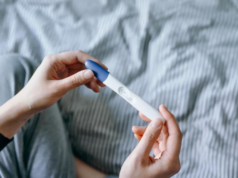 Frau hält einen negativen Schwangerschaftstest in der Hand.