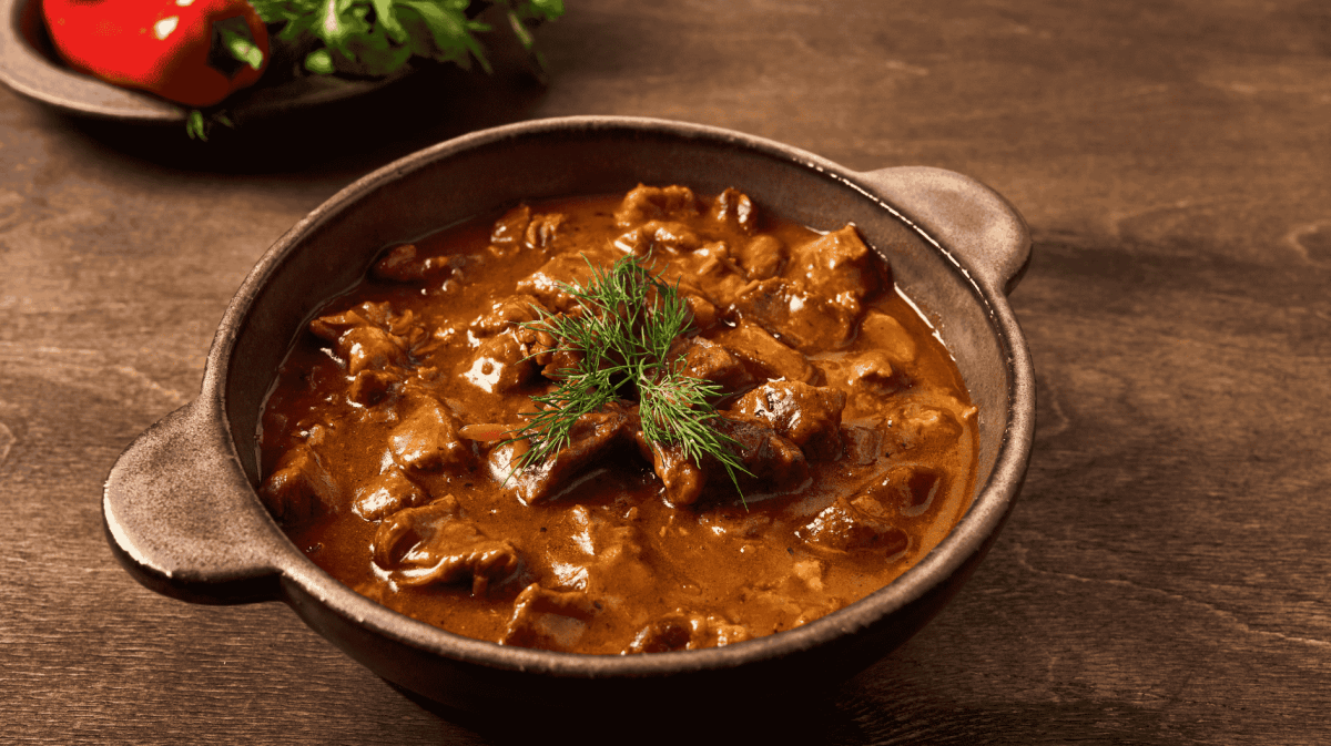 Gulaschsuppe in einem braunen Tontopf.