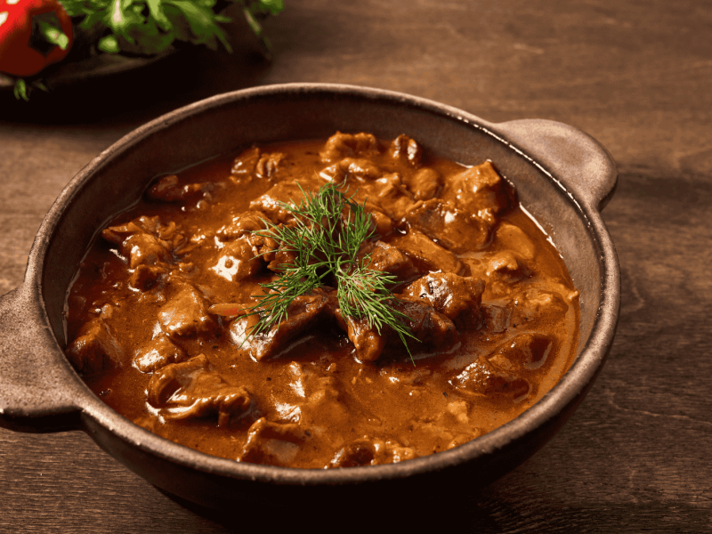 Gulaschsuppe in einem braunen Tontopf.