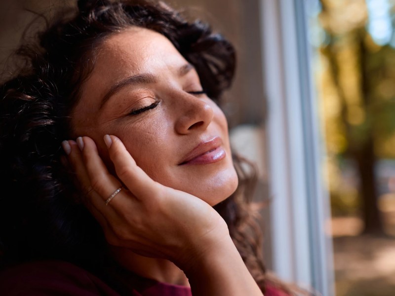 Frau mit reiner Haut, im Hintergrund herbstliche Bäume zu sehen