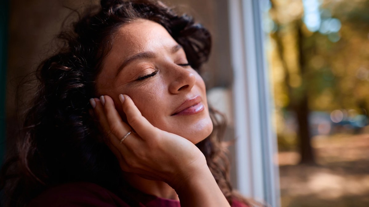 Frau mit reiner Haut, im Hintergrund herbstliche Bäume zu sehen