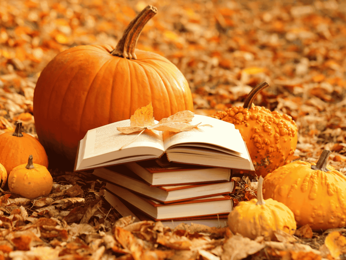 B&uuml;cherstapel und K&uuml;rbisse in Herbstlaub.