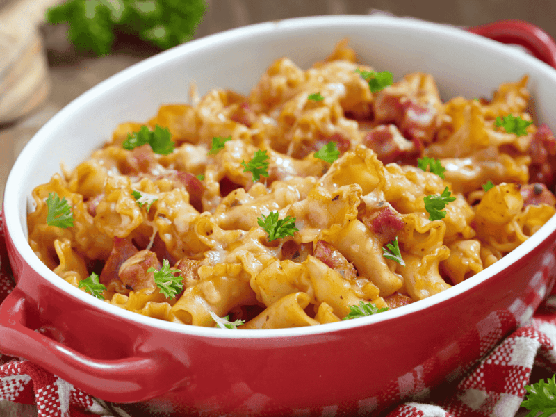 Nudelauflauf mit Schinken in einer roten Auflauflaufform.