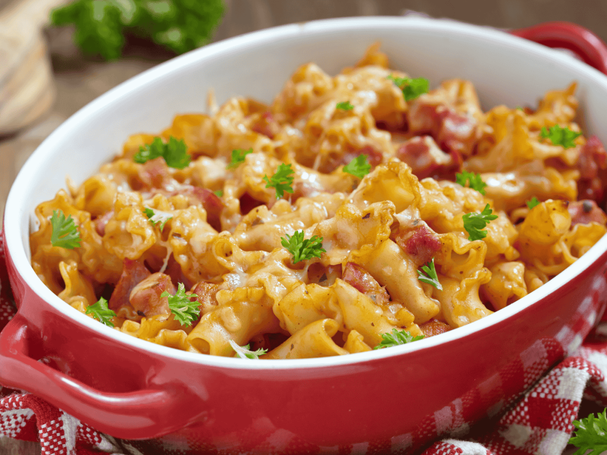 Nudelauflauf mit Schinken in einer roten Auflauflaufform.