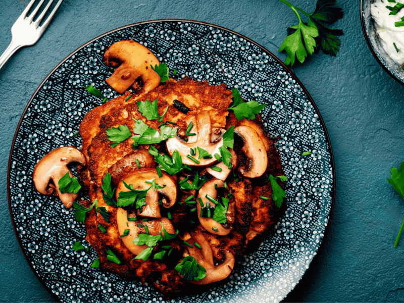 Kartoffelpuffer mit Pilzen auf blauem Teller.