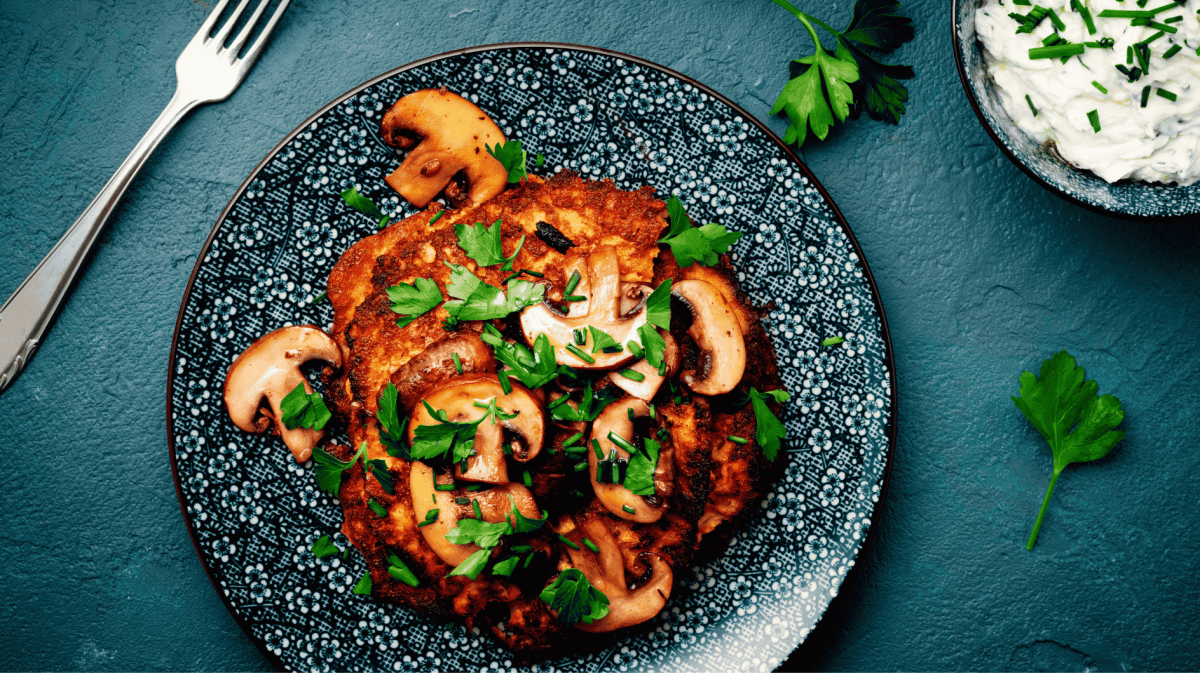 Kartoffelpuffer mit Pilzen auf blauem Teller.