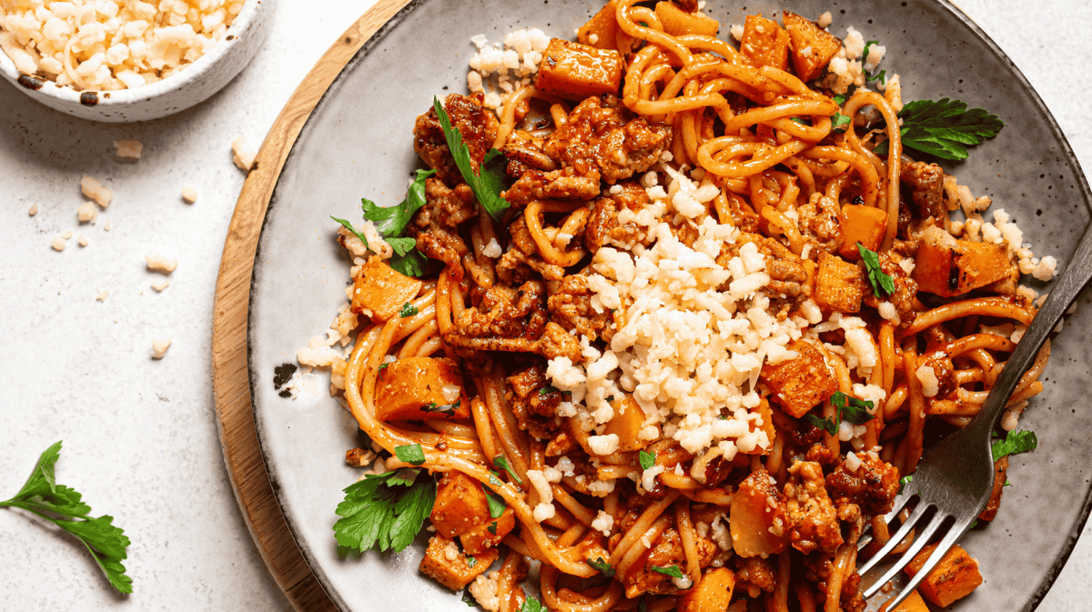 Spaghetti mit Kürbis-Bolognese auf hellem Teller.