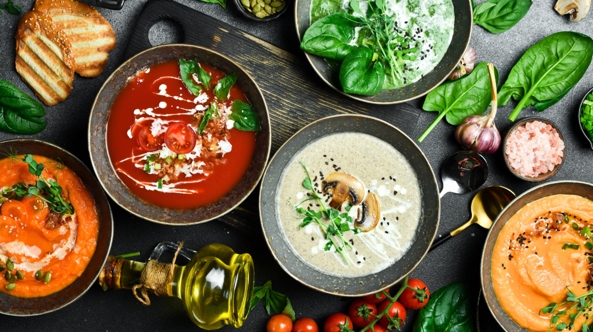 fünf Teller mit verschiedenen Suppen auf einem Tisch