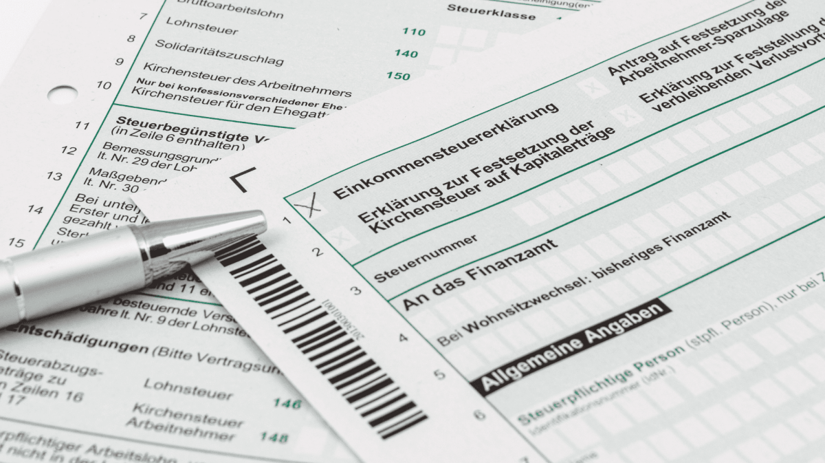 Steuerformulare liegen auf Tisch, ein Kulli daneben.