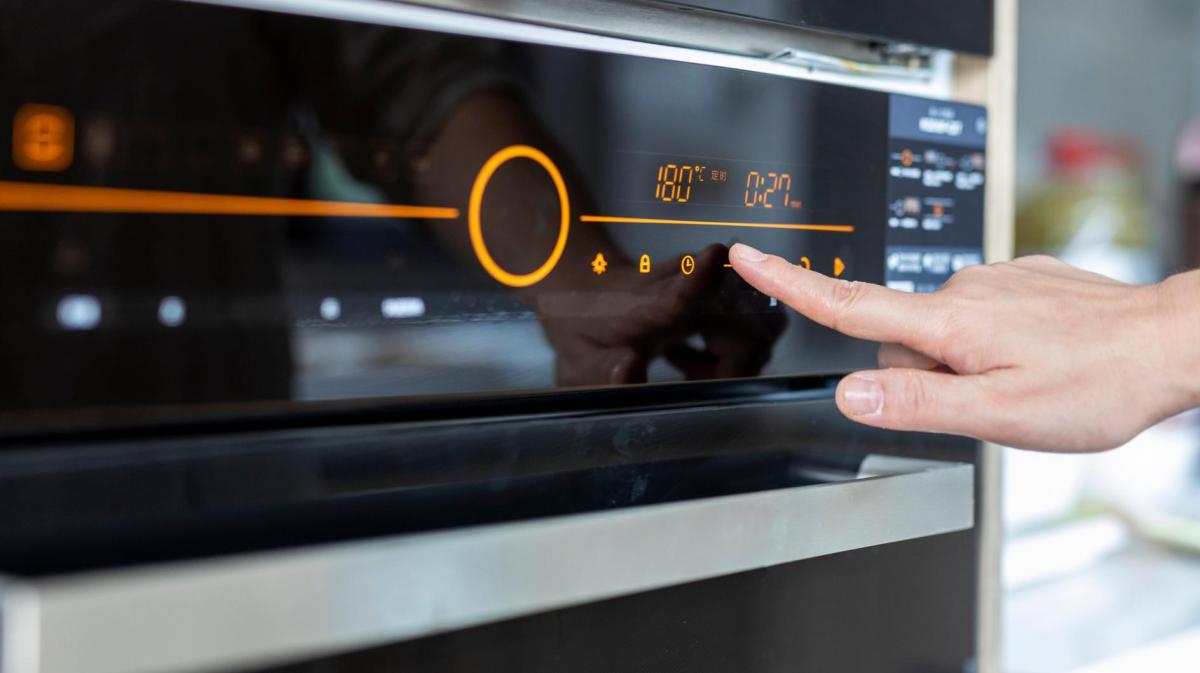 Frau stellt Backofen ein.