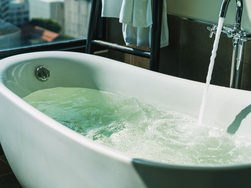 Badewanne, direkt am Fenster, in die Wasser einläuft.